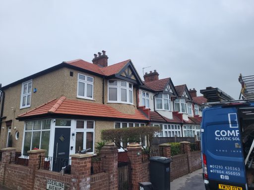 Row of suburban houses with red-tiled roofs, a grey sky above and a blue van parked nearby.