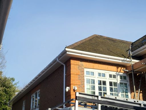 Fascia, Soffits And Guttering In Surrey. A brick building with a sloped roof and large windows against a clear blue sky.