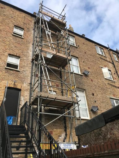Scaffolding set up against a brick building for renovation work.
