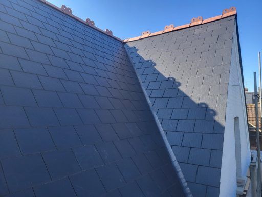Slate Roof Replacement Kingston Slate roof tiles on a sloped roof under a clear blue sky.