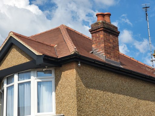 Roof Replacement Wallington House rooftop featuring a chimney and a weathered exterior with blue sky in the background.